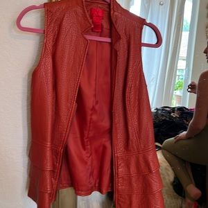 Red  burnt orange) leather sleeveless vest with a zipper. 3 ruffles at bottom